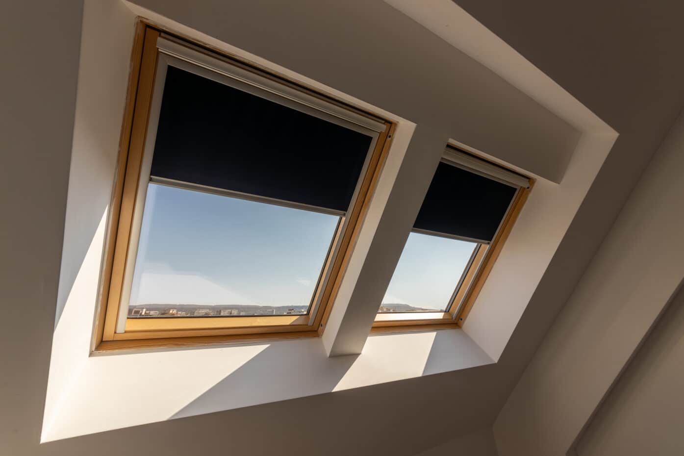 A skylight with partially closed blinds, revealing a bright blue sky on a sunny day.