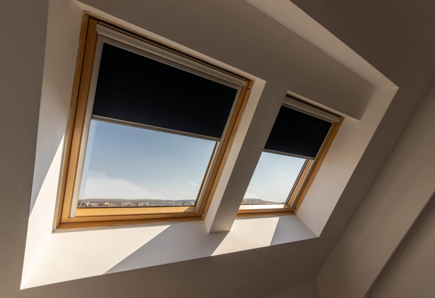 A skylight with partially closed blinds, revealing a bright blue sky on a sunny day.