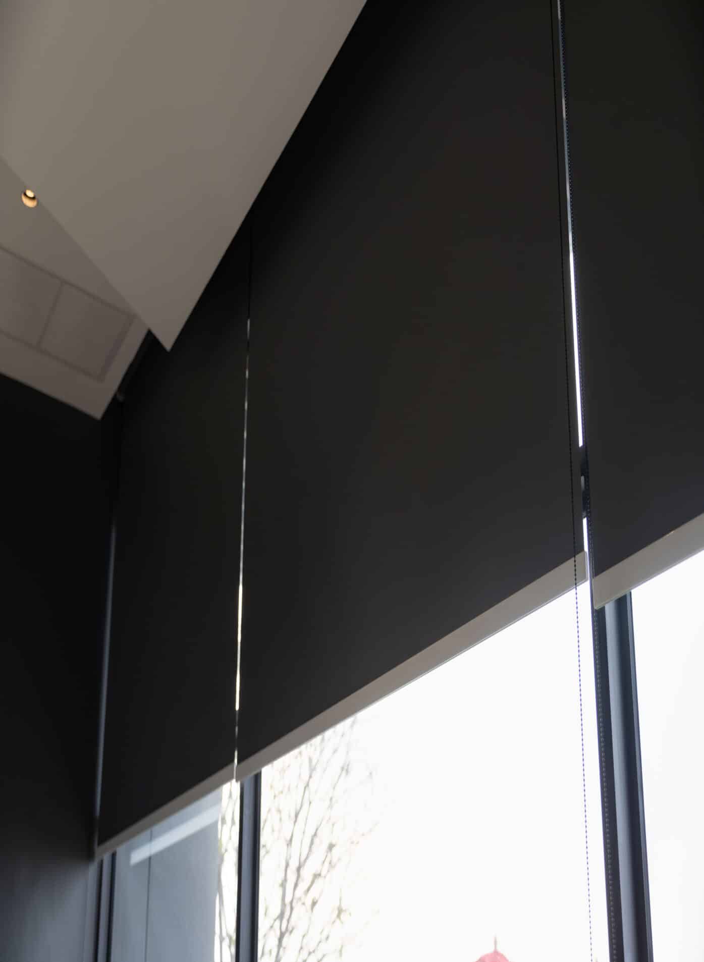 A large office window covered with black blackout blinds, blocking out light for privacy and darkness.