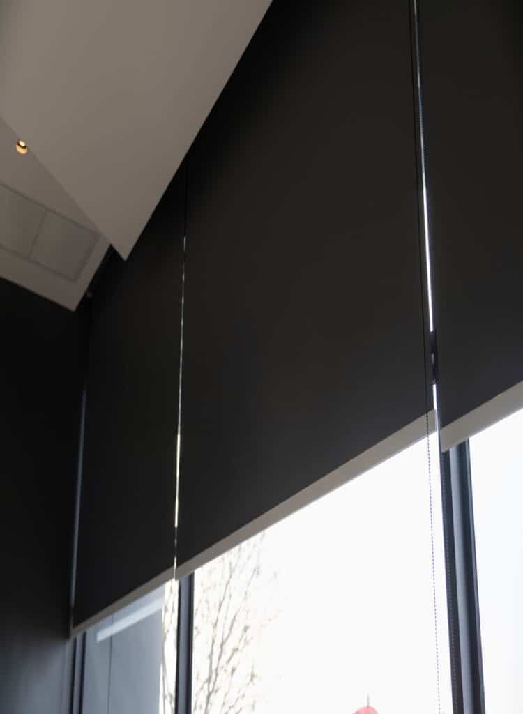 A large office window covered with black blackout blinds, blocking out light for privacy and darkness.