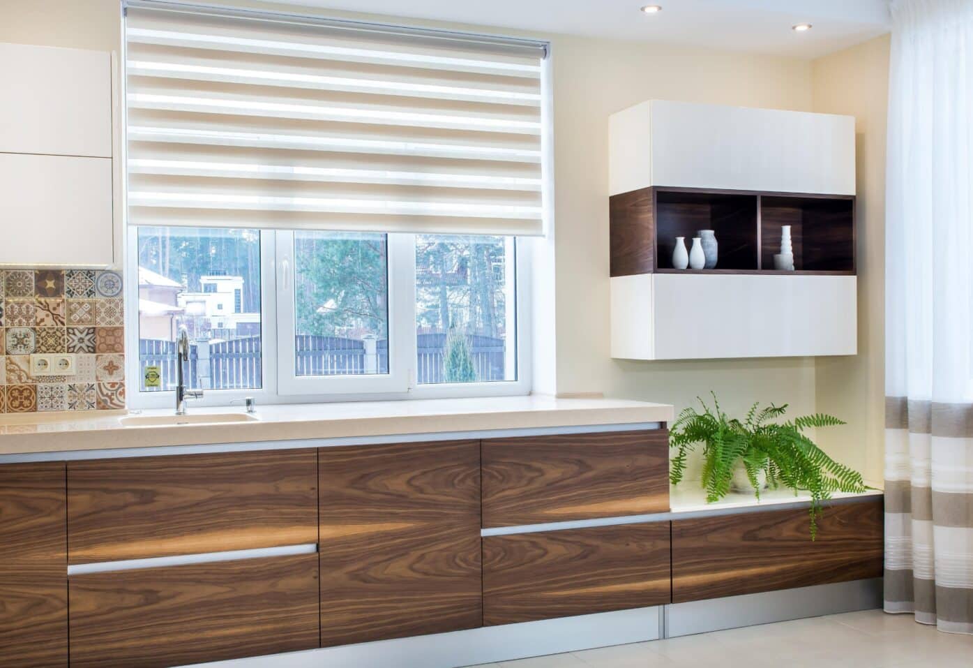 Modern kitchen featuring wooden cabinets, a window, and perfect fit blinds for a sleek, stylish look.